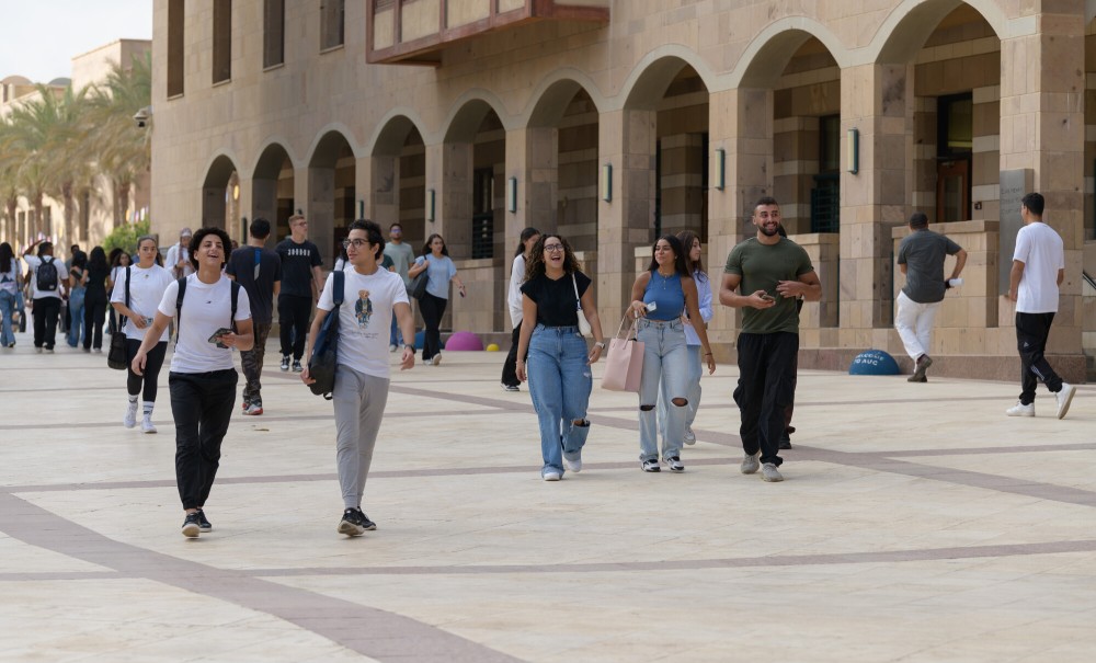 Males and females walking next to a building